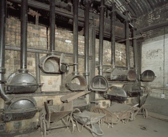 Interior. Retort House: View of retort benches 1 and 2 from NW with coal handling artefacts in foreground.