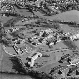 Oblique aerial view centred on the hospital and chapel with the remains of the rig adjacent, taken from the N.