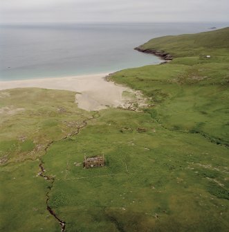 Mingulay, oblique aerial view centred on the remains of the chapel house and enclosure with the remains of the township, chapel and graveyard and the school and schoolroom adjacent, taken from the NW.