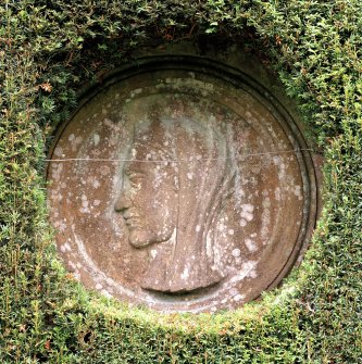 Detail of stone roundel set into wall of formal garden.