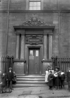 Detail of main entrance with group of children standing in front of steps.