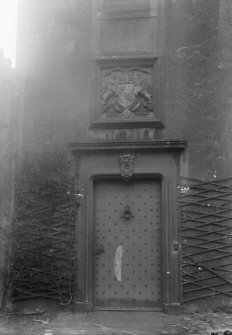 Detailed exterior view of the entrance doorway seen from the West North West. Above the studded door is a stone relief of a coat-of-arms of two lions flanking a crest dated 1831 and with the initials TDL and CAC.