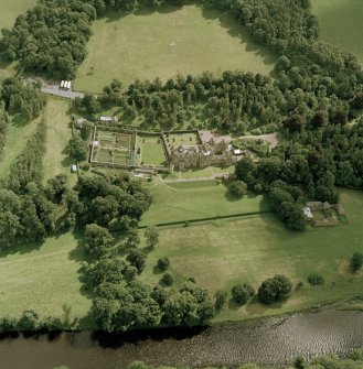 Oblique aerial view of Abbotsford centred on the country house with tea room, gardens and stables adjacent, taken from the NW.