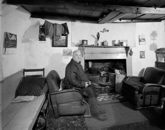 Tiree, Kilmoluag, interior.
View of kitchen with occupant Mr MacKinnon seated in chair.