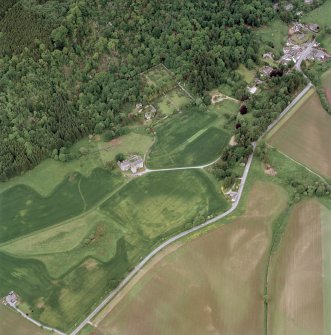 Oblique aerial view of Castle Menzies centred on a tower house, well, walled garden and military road, and the crop marks of pits, a garden and linear cropmarks, taken from the SSW.