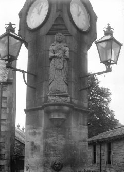 Detail of middle shaft from E showing statue of Mrs Gifford, gas lanterns and clockfaces.