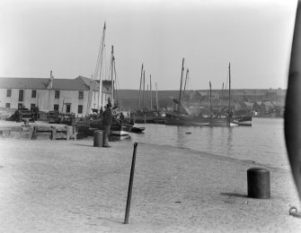 View of a man, dock buildings and boats at the Old Harbour, Montrose.