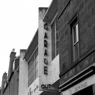 Detail of the lettering on the front of the garage: ' GARAGE' and 'OUT' seen from the South, with the garage in disrepair.