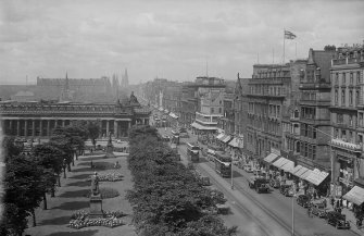 General view of Princes Street showing the gardens and Royal Academy, and a busy street with cars, buses and trams