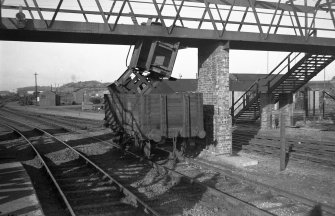 Scanned image of negative showing part of the footbridge at Rosyth Station with single wagon freight accident underneath, taken from the E.