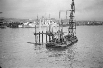 Scanned image of negative showing temprary pontoon with drilling barge alongside in main basin with destroyers in the background, taken from the SE.