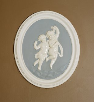 Interior. Entrance hall, detail of oval wall plaque with putti