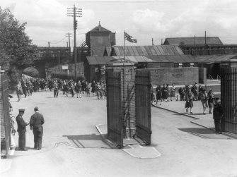 View from WSW of factory entrance main gate (E) with an air-raid shelter and Bishopton station in the background.