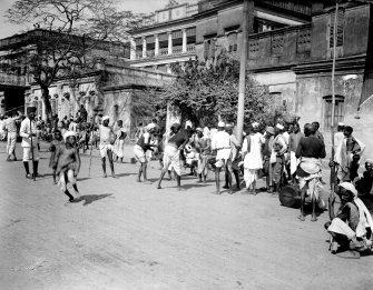 Street scene with possible game or betting with watching policeman, probably Kolkata.