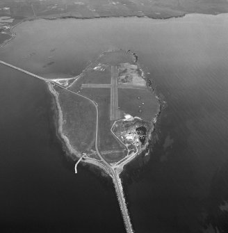 Aerial view, Orkney, Lamb Holm taken from the SW.  Visible is the modern grass landing strip, Lamb Holm World War II coast battery, the concrete hut bases of the former prisoner-of-war camp, the Italian Chapel and parts of Churchill Barriers Nos. 1 and 2.