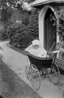 Photograph of David Beveridge (1886-1915), son of Erskine Beveridge, in perambulator outside garden house at Kirkmay House, Crail.
