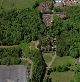 Oblique aerial view of Loudoun Castle, gardens, estate policies and fairground, taken from the W.