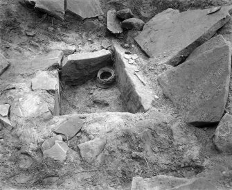 View of Kalemouth cairn during excavation showing cist and food-vessel urn.