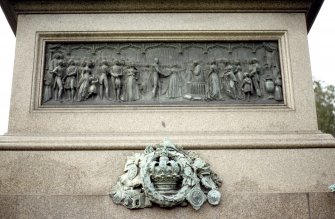 View of E side of Albert Memorial, showing bronze panel depicting the marriage of Prince Albert and Queen Victoria, and a bronze group of objects including a crown and medals.