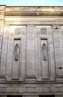 View of part of W facade of National Library of Scotland, showing carved personifications of Medicine (left) and Science (right), with Celtic motif roundels above.