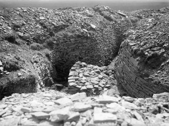 Wall of broch on right behind buttress, S: passage and revetment in addition to rampart behind.