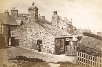 View of cottage in Holyrood Park from East, with woman sitting on window frame.
Titled: 'Jeannie Dean's Cottage, St. Leonards, Edinburgh.  1170.  G.W.W.'
Since demolished.