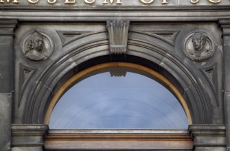 View of portrait medallions of Queen Victoria (left) and Prince Albert (right), in spandrels of central entrance arch of main facade, Chambers Street.