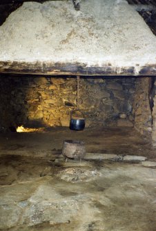 Camserney Farm, Long House, W end: wattle and daub hanging lum above the central stone hearth in the older, western part of the long house. The timber balk is visible behind the hearth stone