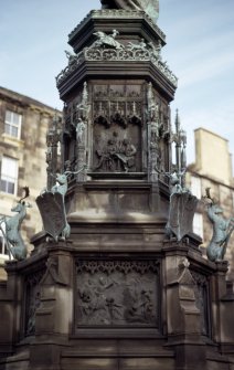 View of SW side of pedestal of Monument to the Duke of Buccleuch, showing bronze panels. The upper panel shows the Duke planning Granton Harbour; the lower panel shows the burning of Catslack Tower in Yarrow by the English in 1548.