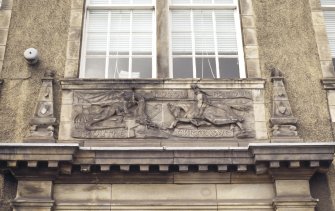 View of panel carved with St George and the Dragon, above doorway of main school building.