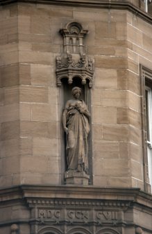 View of sculpture representing 'Prudentia', at corner of building, first floor level.