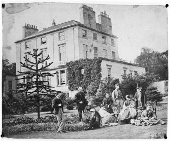 General view of the garden facade with a family group in the foreground seen from the East. The family group is probably Duncan McLaren, died 1886, (Lord Provost of Edinburgh) and his third wife Priscilla Bright, daughter of Jacob Bright and sister of the Right Honourable John Bright, and the children of his three marriages.