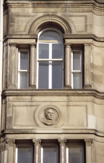 View of carved portrait head, in medallion above third floor window on W bay of Princes Street facade.