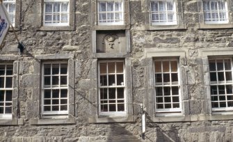 View of panel carved with cordiners' emblem, above first floor windows of 197 Canongate.