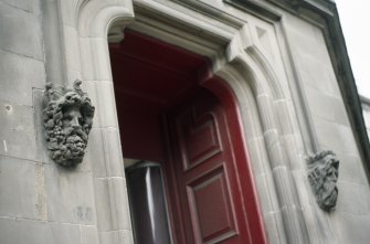 View of label-stop heads of Bacchus (left) and Neptune (right), either side of door to 37 Bernard Street.