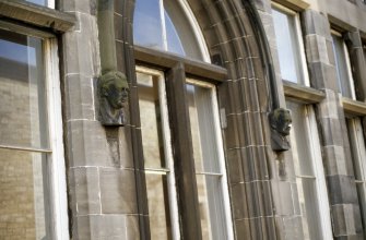 View of label-stop heads of Sir Walter Scott (left) and Robert Louis Stevenson (right), either side of ground floor window.