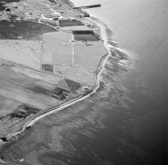 Hoy, Crockness, oblique aerial view, taken from the ESE, centred on the Martello Tower and a curving linear soilmark, and showing Rinnigill Military Camp and a crane in the background.