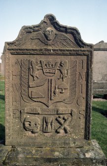 General view of gravestone with winged soul, shield and skull motif inscribed 'Memento Mori'.
