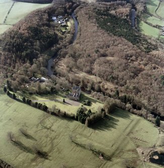 Oblique aerial view centred on the tower-house and earthworks with the stables and cottage adjacent, taken from the east south east.