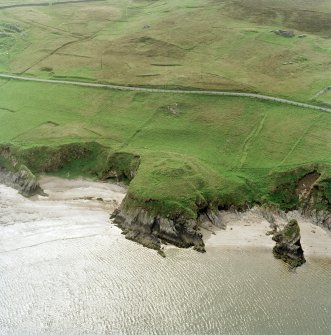 Oblique aerial view centred on the remains of the broch with the remains of the farmstead, enclosure and field-system adjacent, taken from the E.