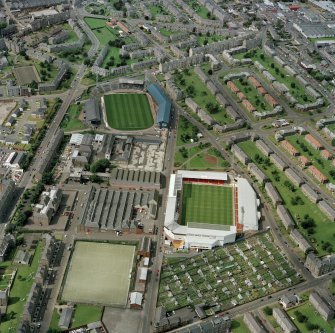 Oblique aerial view of Dundee centred on the stadium with stadium and jute works adjacent, taken from the SE.