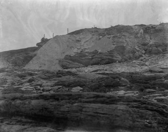 Excavation photograph: Spoil dumped over cliff, entrance to house 1 visible above.