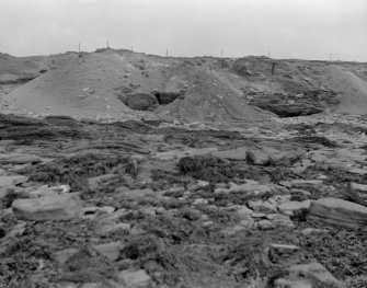 Excavation photograph: Spoil dumped over cliff.
