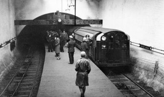 Glasgow, Partick Cross underground station, interior
General view of platform and tracks with train in station and people on platform.