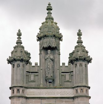 Detail of crocketed pinnacles and statue in niche of tower on N face.