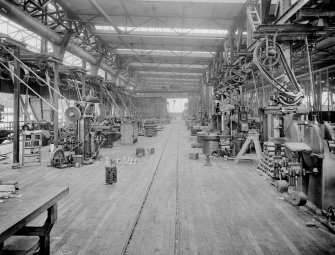 Glasgow, 739 South Street, North British Engine Works.
General view from South-West. Bay 'B', Upper floor level, main workshop. On the left hand side of the view, in the foreground a group of milling machines and in the background are capstan and turret lathes, (these lathes are shown in photo No. 1). On the right hand side is a pair of disc grinders, (ready to be installed) above which is located the line shaft electric drive motors and morse chain drive belt, (link type belt) and guard. The drive motor made by Westinghouse Co. Manchester, England). Behind the drive motor stand are several medium size shaping machines. On the right hand side of the shop railway lines a row of vertical boring mills all with individual electric drive motors can be seen. Note the hot air heating duct mounted in the columns along the left side of the bay/ view.
