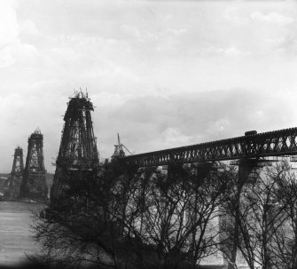 View of the North cantilever of the Fife erection under construction seen from the North Queensferry shore.
Insc. 'N. Cantilever.  F. Bridge.  C. Cameron.'
Lantern slide.