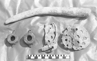 Various objects associated with the working of the ship. Top, a deep-sea sounding-lead; bottom left, two copper-alloy coaks or bearings from wooden sheaves or 			perhaps the mounting of a swivel-gun; bottom right, two perforated lead discs, probably parts of pump filters. Scale in centimetres and inches.