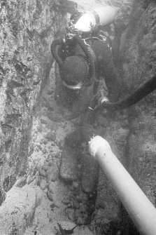 Excavating a narrow cleft in Gulley A with a suction dredge reveals two lead ingots.