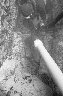 Excavating a narrow cleft in Gulley A with a suction dredge reveals two lead ingots.